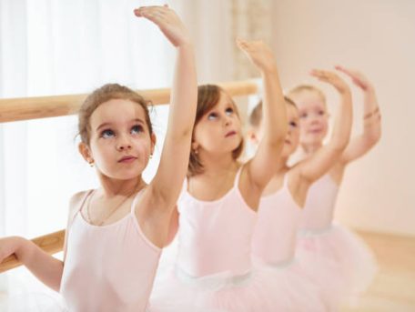 Little ballerinas preparing for performance by practicing dance moves.